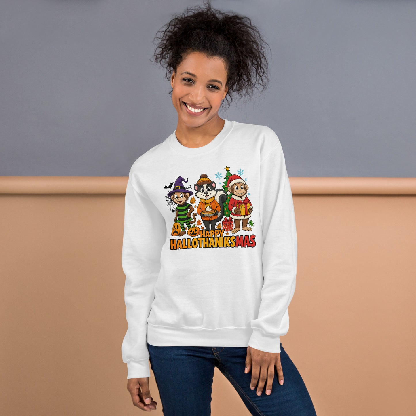 Woman wearing a white sweatshirt with a festive “Hallothanksmas” design featuring Halloween, Thanksgiving, and Christmas characters against a neutral background