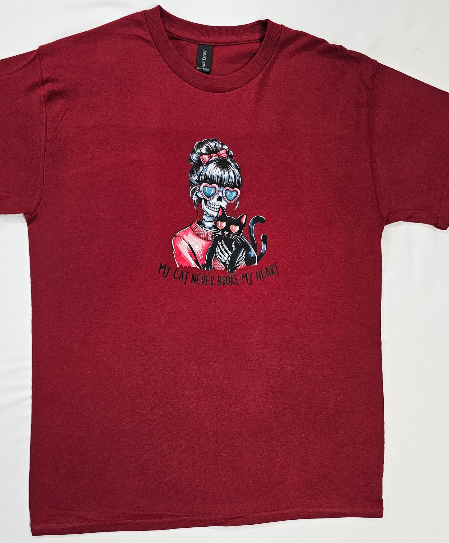 Maroon t-shirt with a graphic of a skeleton holding a cat and text on a white background