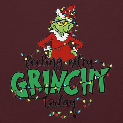 Grinch character with Christmas lights and text 'Feeling extra Grinchy today' on a dark red background