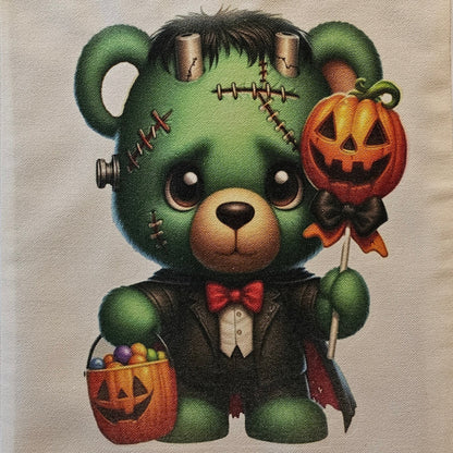 Tote bag with a green teddy bear design featuring Halloween elements on a plain background.