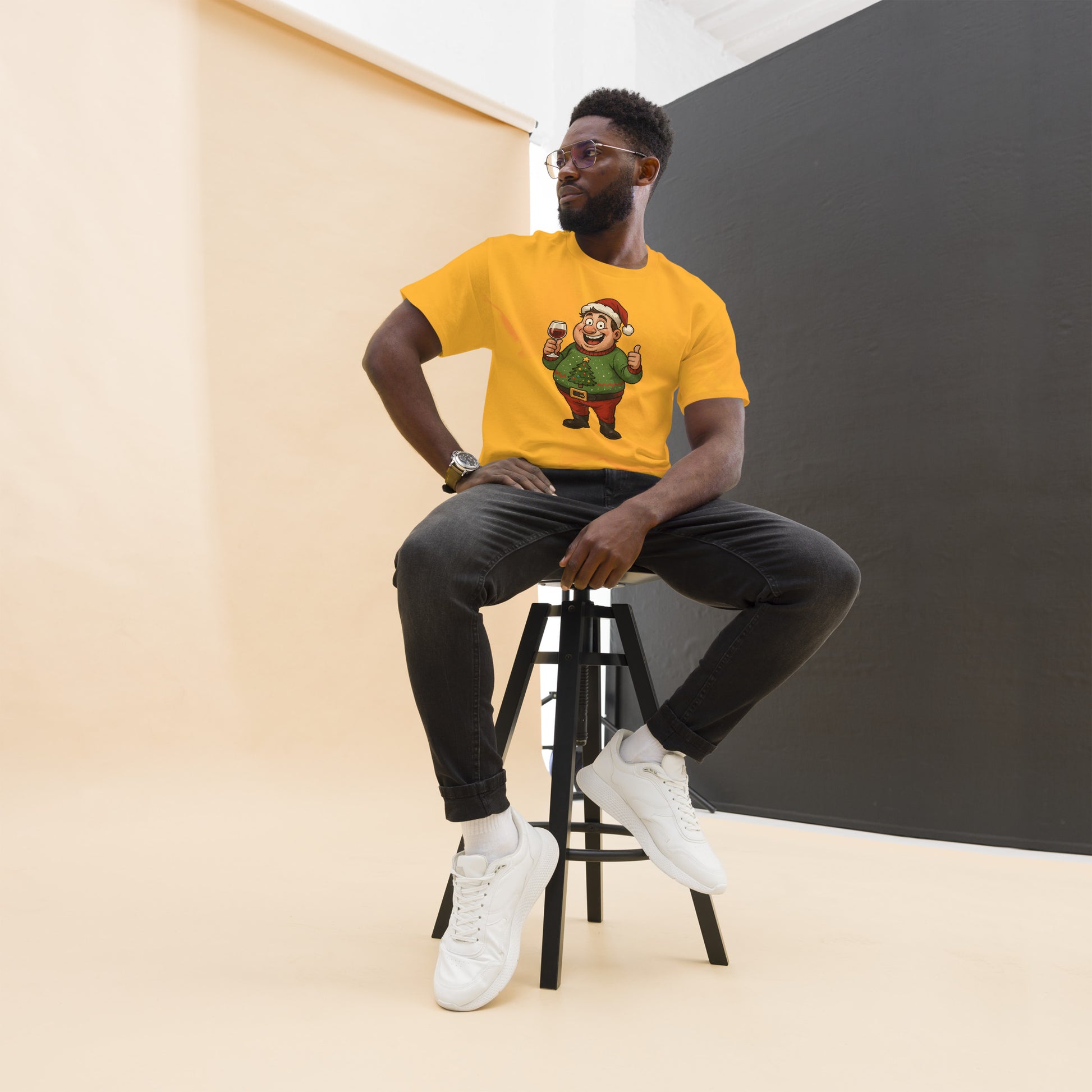 Man sitting on a stool wearing a yellow t-shirt with a graphic design, against a plain background.