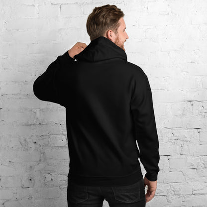 Man wearing a black hoodie standing against a white brick wall