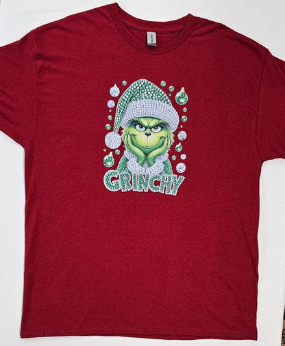 Red t-shirt with a graphic of a green character wearing a Santa hat and the word 'GRUNCHY' on a white background.