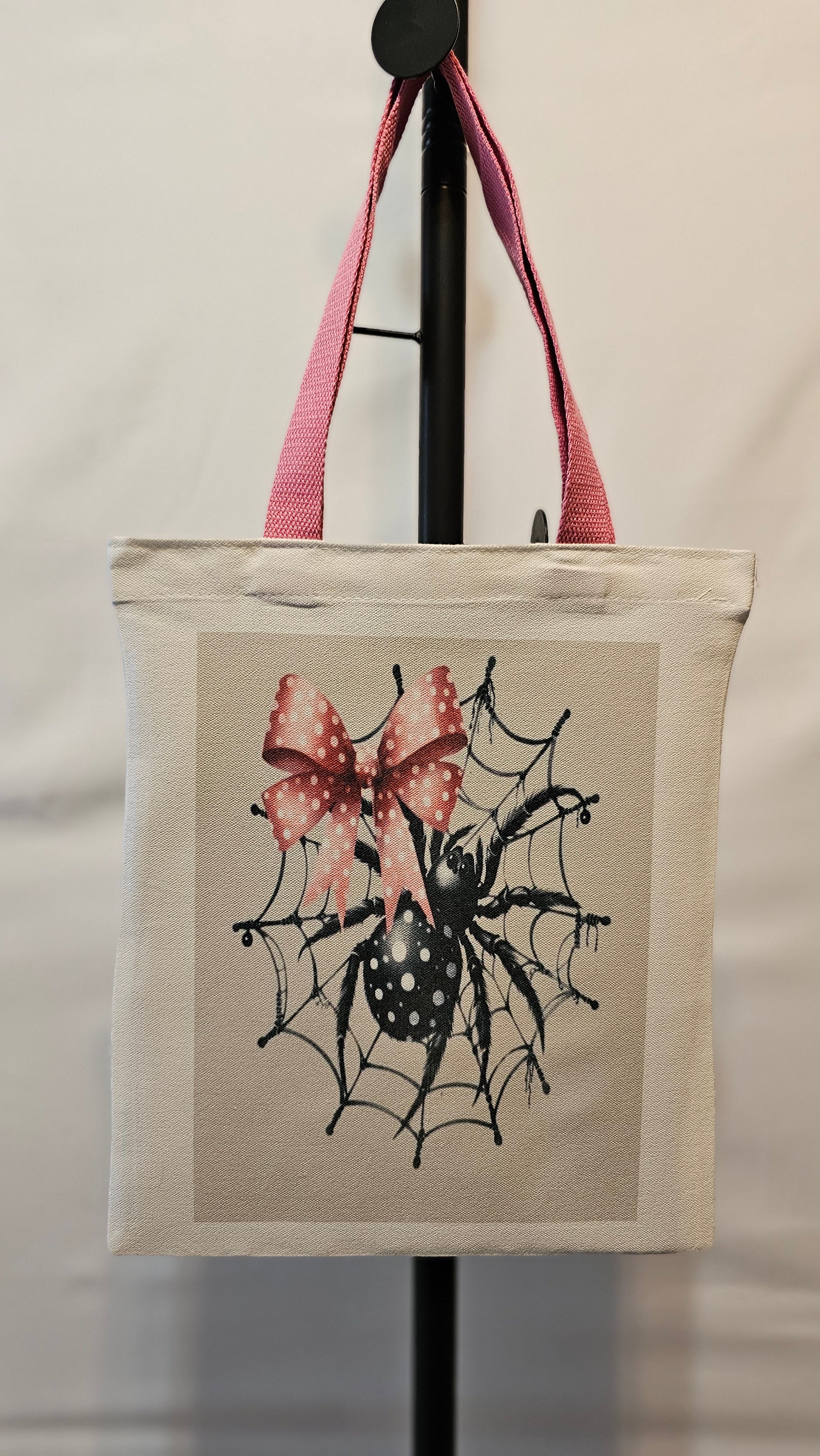 Small tote with spider design and pink bow on a white background