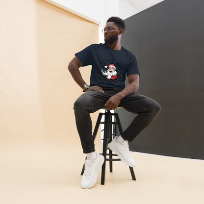 Man sitting on a stool wearing a black t-shirt with a graphic design, black pants, and white sneakers.