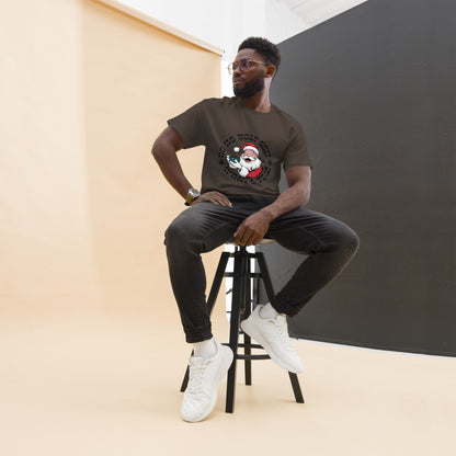 Man sitting on a stool wearing a brown t-shirt with a graphic design, black pants, and white sneakers.