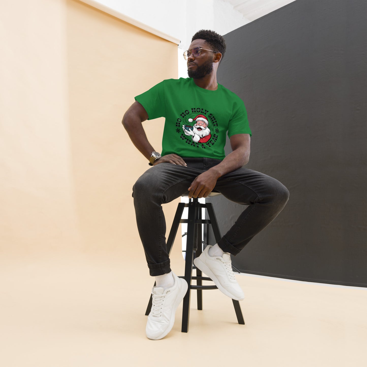 Man sitting on a stool wearing a green t-shirt with a graphic design.