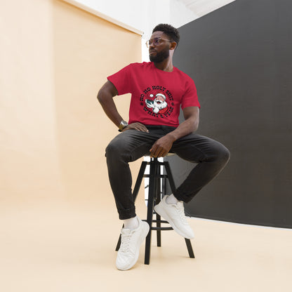 Man sitting on a stool wearing a red t-shirt with a graphic design, black pants, and white sneakers.