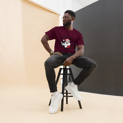 Man sitting on a stool wearing a maroon t-shirt with a graphic design, black pants, and white sneakers.
