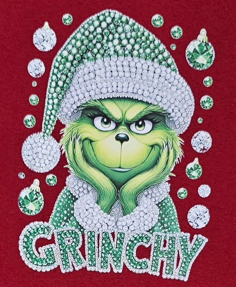 Red t-shirt with a graphic of a green character wearing a Santa hat and the word 'GRUNCHY' on a white background.