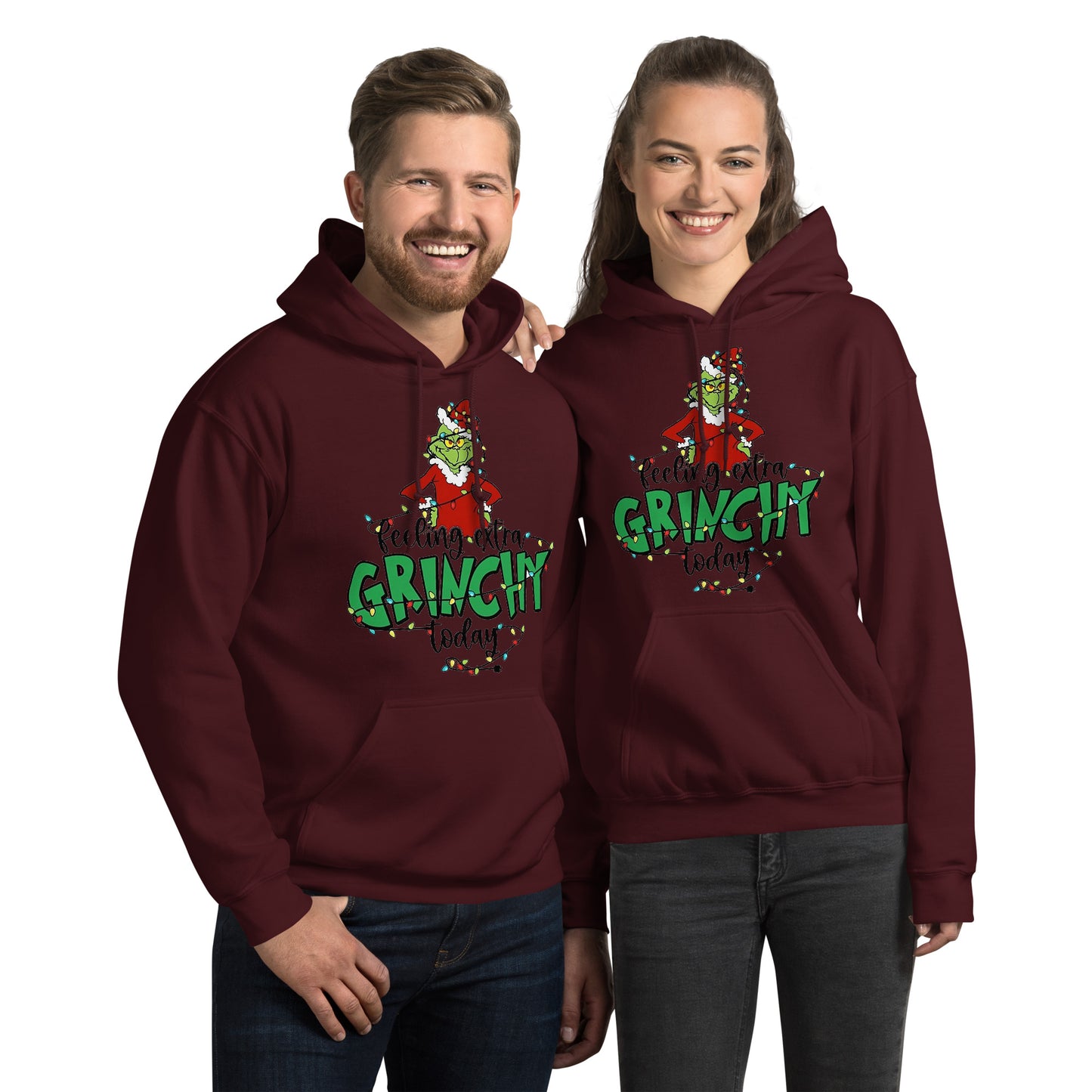 Two people wearing matching maroon hoodies with a Grinch design on a white background