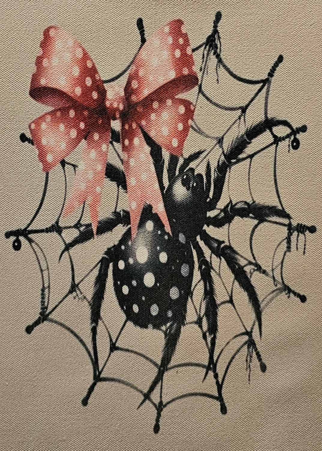 Small pouch with spider design and pink bow on a white background