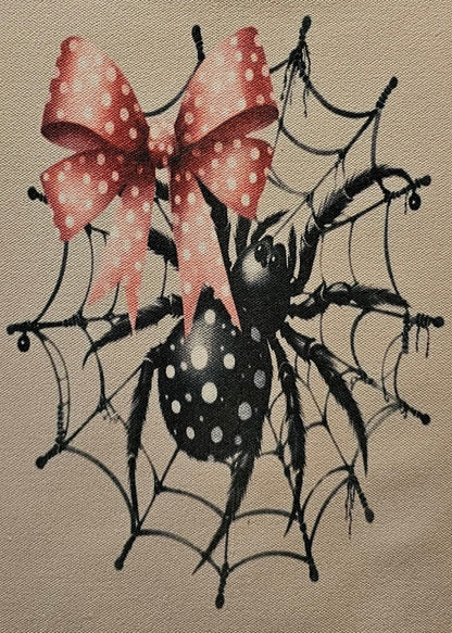 Small pouch with spider design and pink bow on a white background